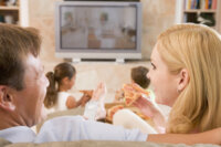 Couple Enjoying Pizza In Front Of TV