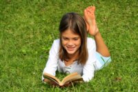 petite fille lisant dans l’herbe