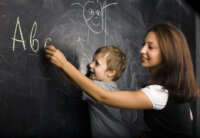 little cute boy with young teacher in classroom studying