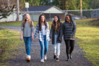 Group of young girls holding hands and laughing while walking on